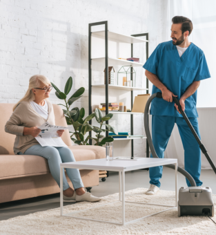 male nurse cleaning the living room and a elderly woman sitting 