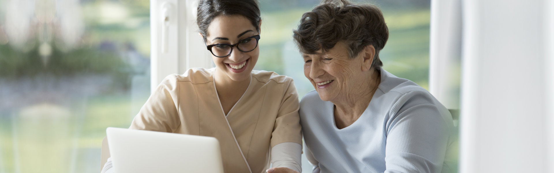 nurse and elderly woman looking at the laptop